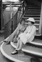 Coco Chanel Sits on Stairs with Unidentified Woman, 1957
