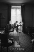 Coco Chanel Writes at Desk in Window, Head Down, 1957