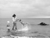 Kennedys, Hyannis Beach, Jackie Swinging Caroline with Cousin in Water, 1959