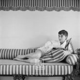 Audrey Hepburn on Striped Sofa, Reclines, Book Open, 1954