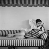 Audrey Hepburn on Striped Sofa, Arm Back, Head Tilted Smiling, 1954