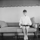 Audrey Hepburn on Striped Sofa, Faces Forward with Book Open, 1954