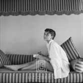 Audrey Hepburn on Striped Sofa, Leans Forward Writing, 1954