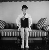 Audrey Hepburn on Striped Sofa, Hands on Closed Book, 1954